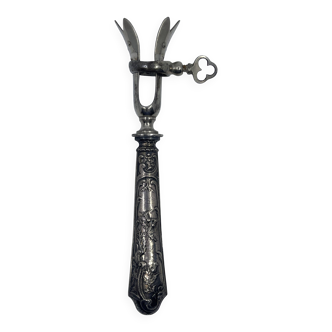 Silver-plated metal leg of lamb handle with engraved thistle flower patterns.