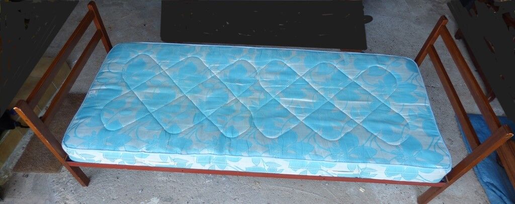 Single bed with wooden headboard and footboard and metal box spring