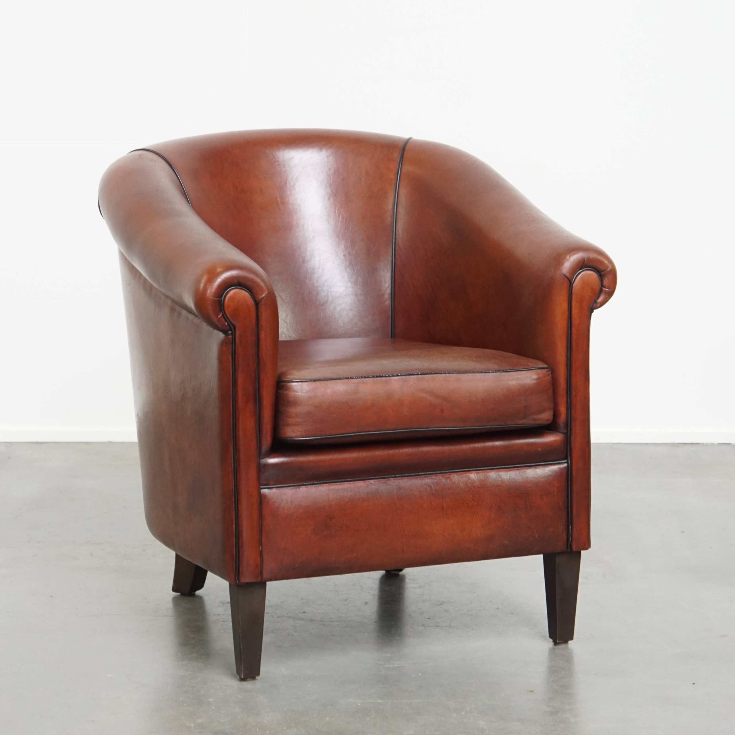 Sheepskin club armchair in a warm deep colour finished with black piping