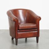 Sheepskin club armchair in a warm deep colour finished with black piping