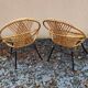 Paire de fauteuils coquilles ou corbeille en rotin tressé, pieds en métal