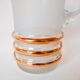 set composed of a pitcher and two large white granite glasses with gold edging from the 60s