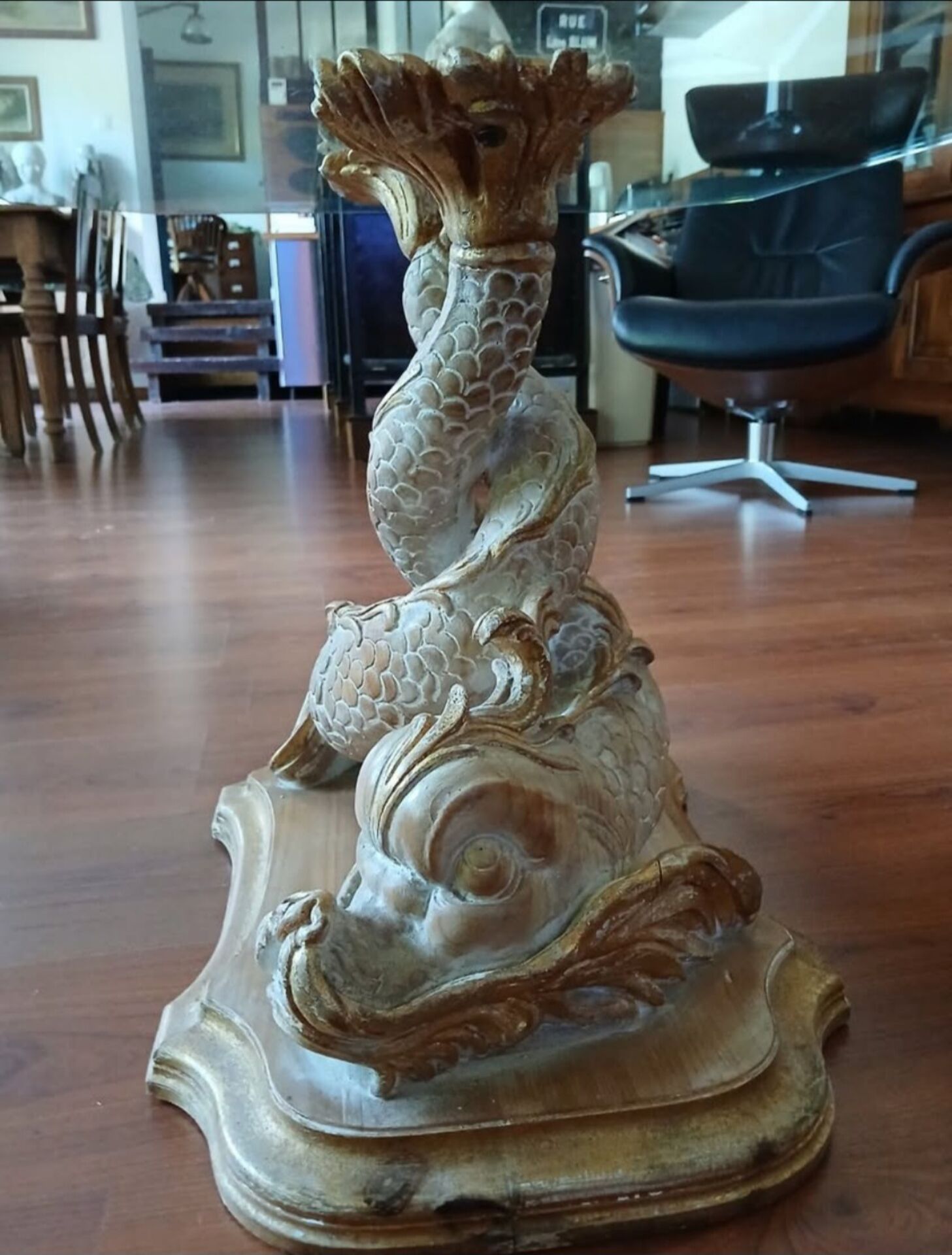 Glass table with carved wooden legs featuring intertwined fish.