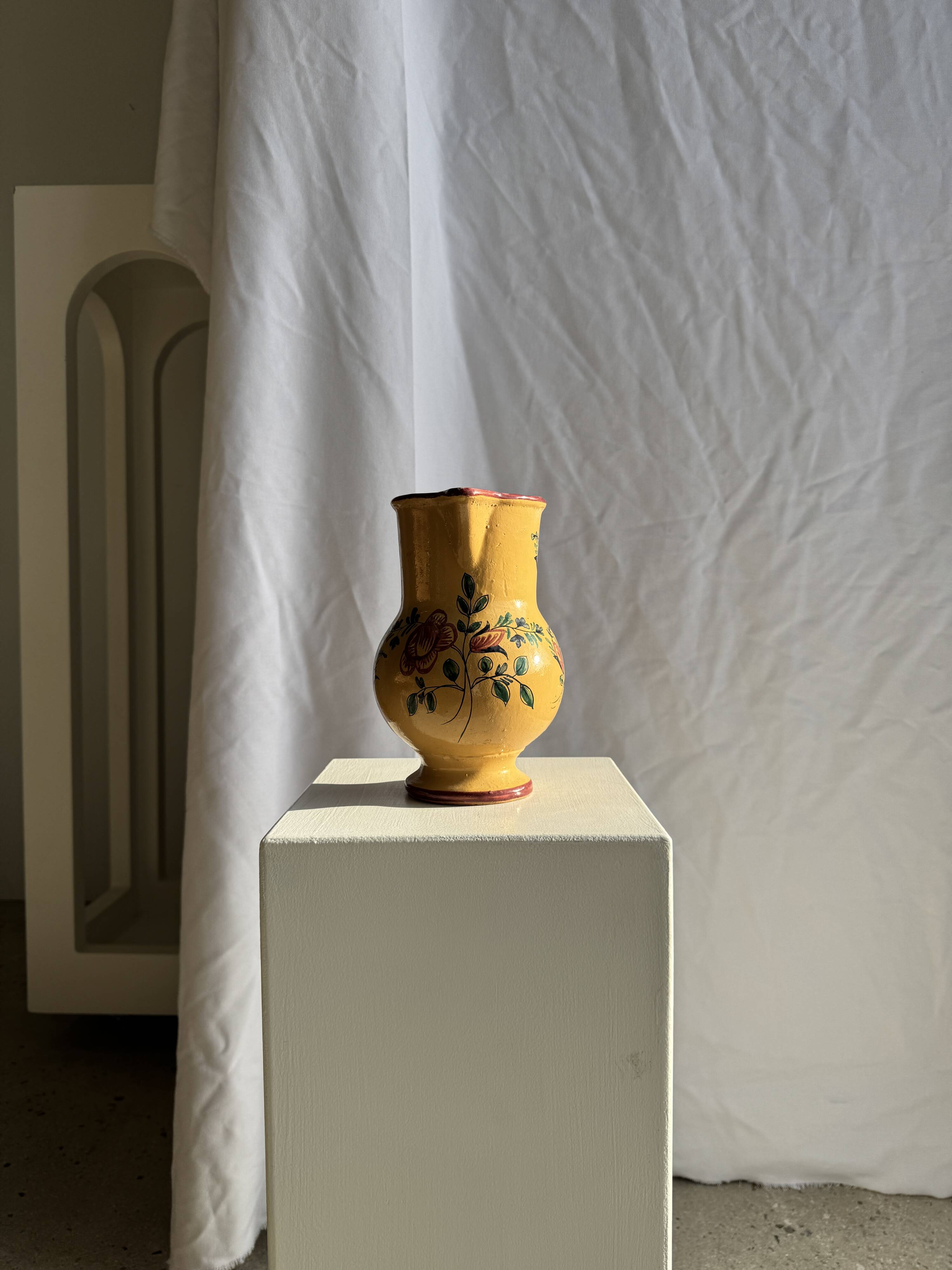 Large antique handmade ochre yellow jug with a pink flower pattern.