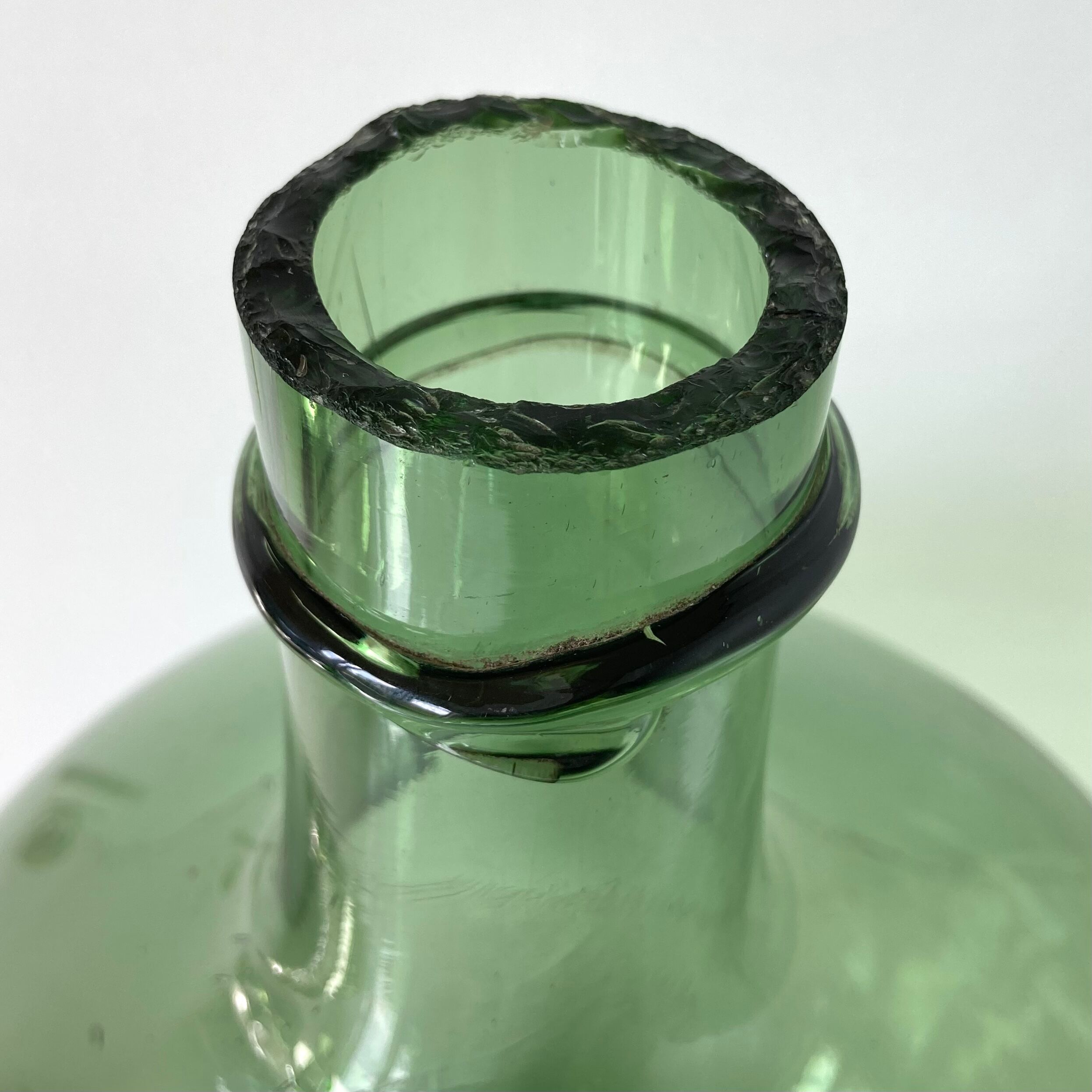 Old demijohn in green glass with ringed neck and hammered opening