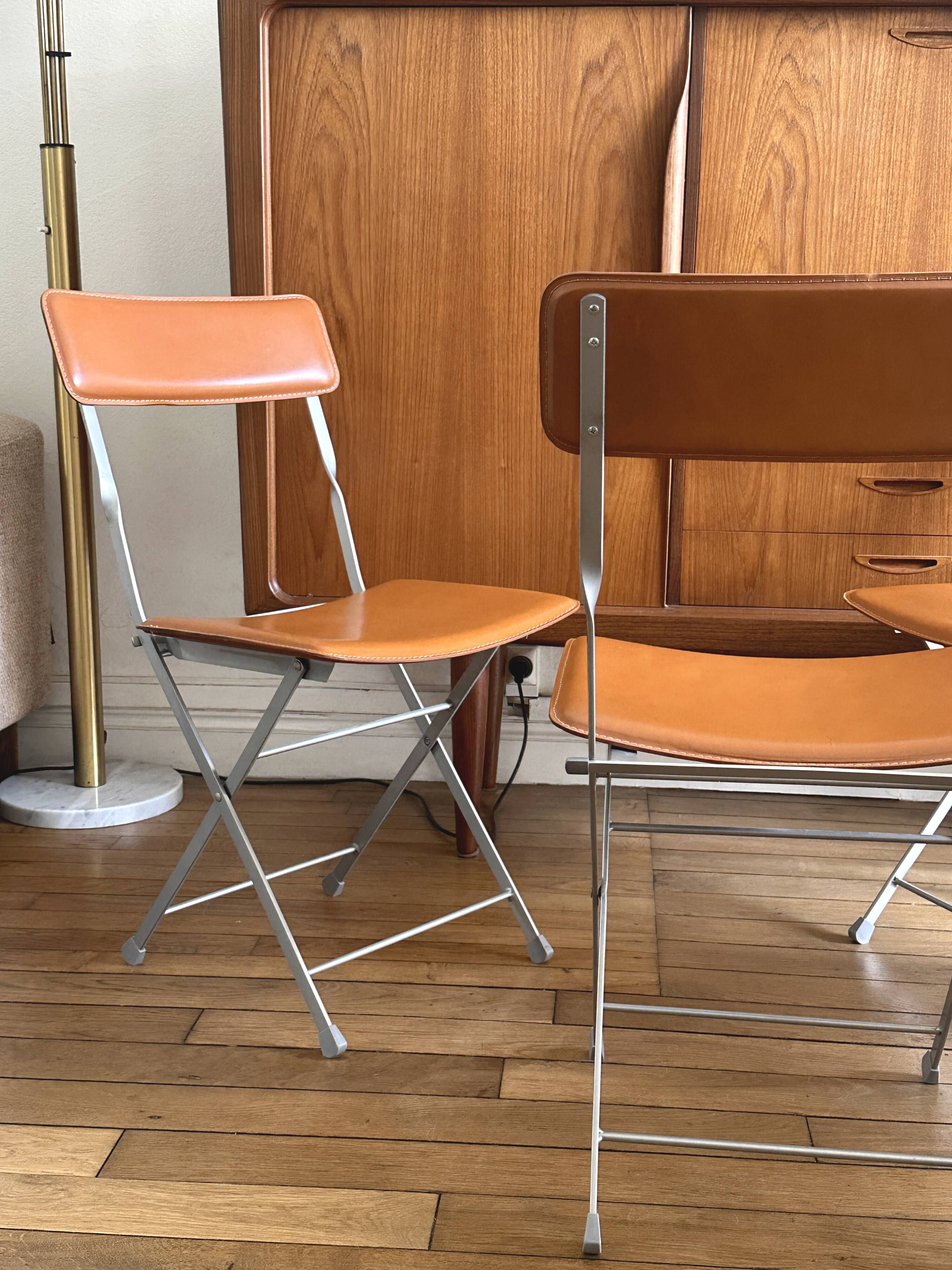 4 folding Sintesi chairs for DWR Lina in metal and vintage camel leather.