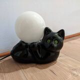 Black cat playing with its globe table lamp