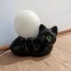 Black cat playing with its globe table lamp