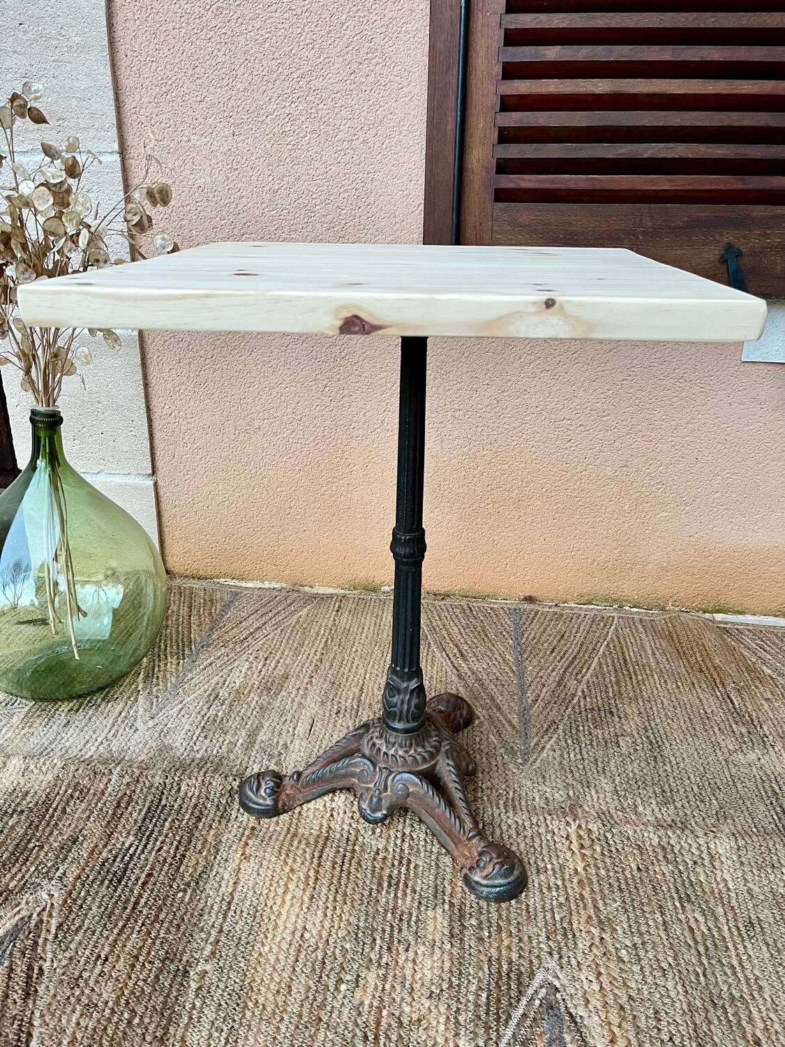 Bistro table with a raw wood top and a central cast iron base.