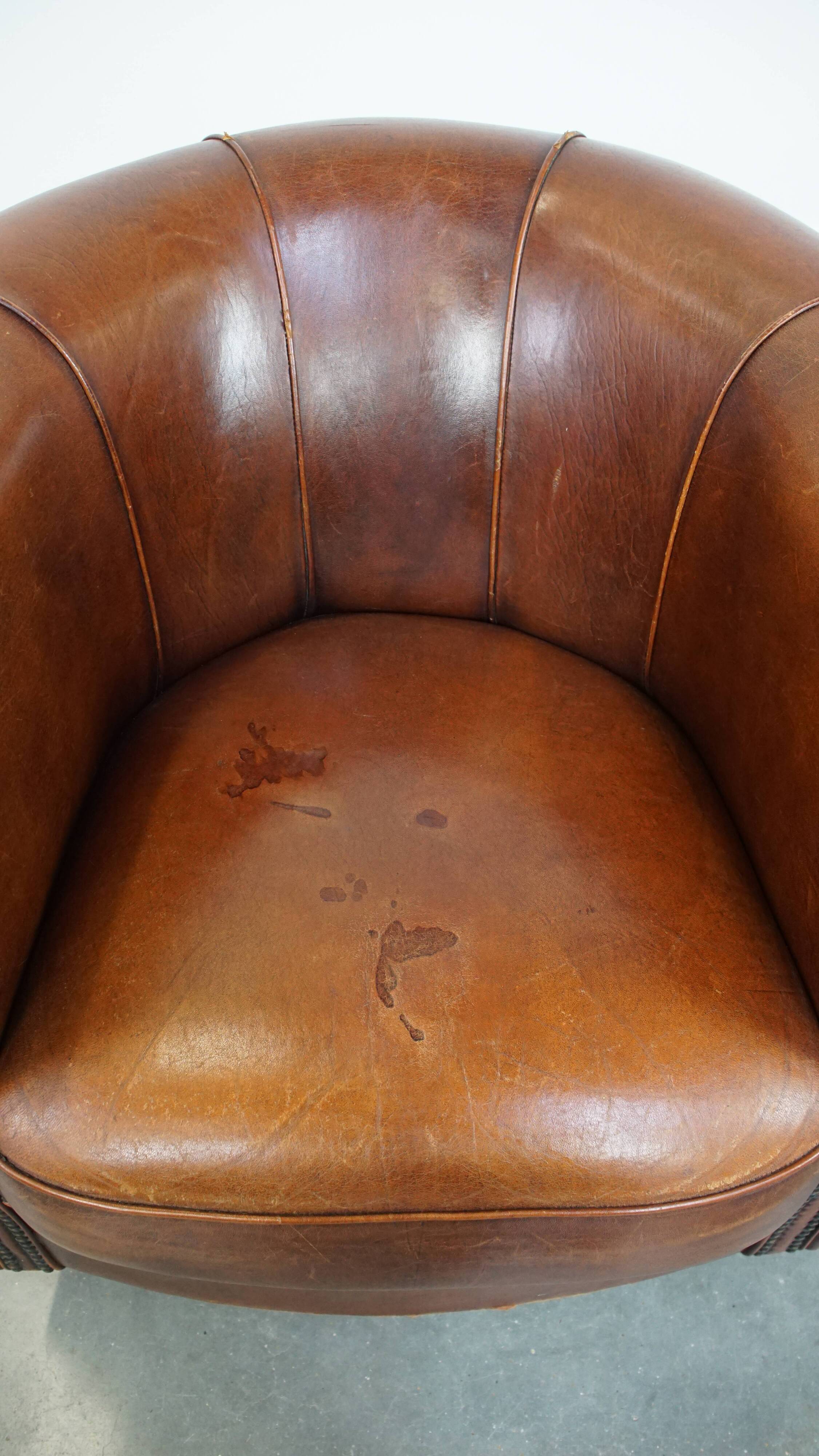 Sheep leather club chair in a cognac color and finished with piping