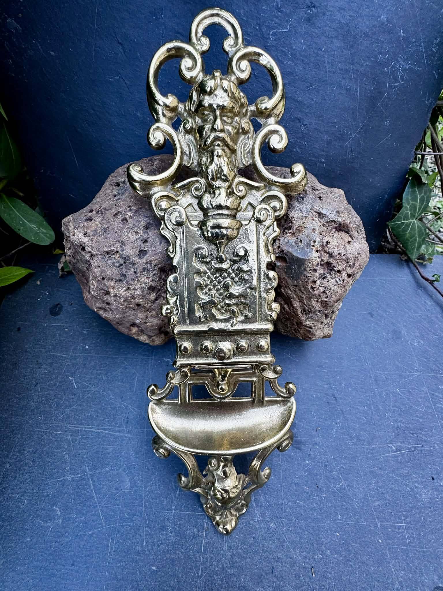 Brass magazine rack with baroque mask, wall-mounted match holder.