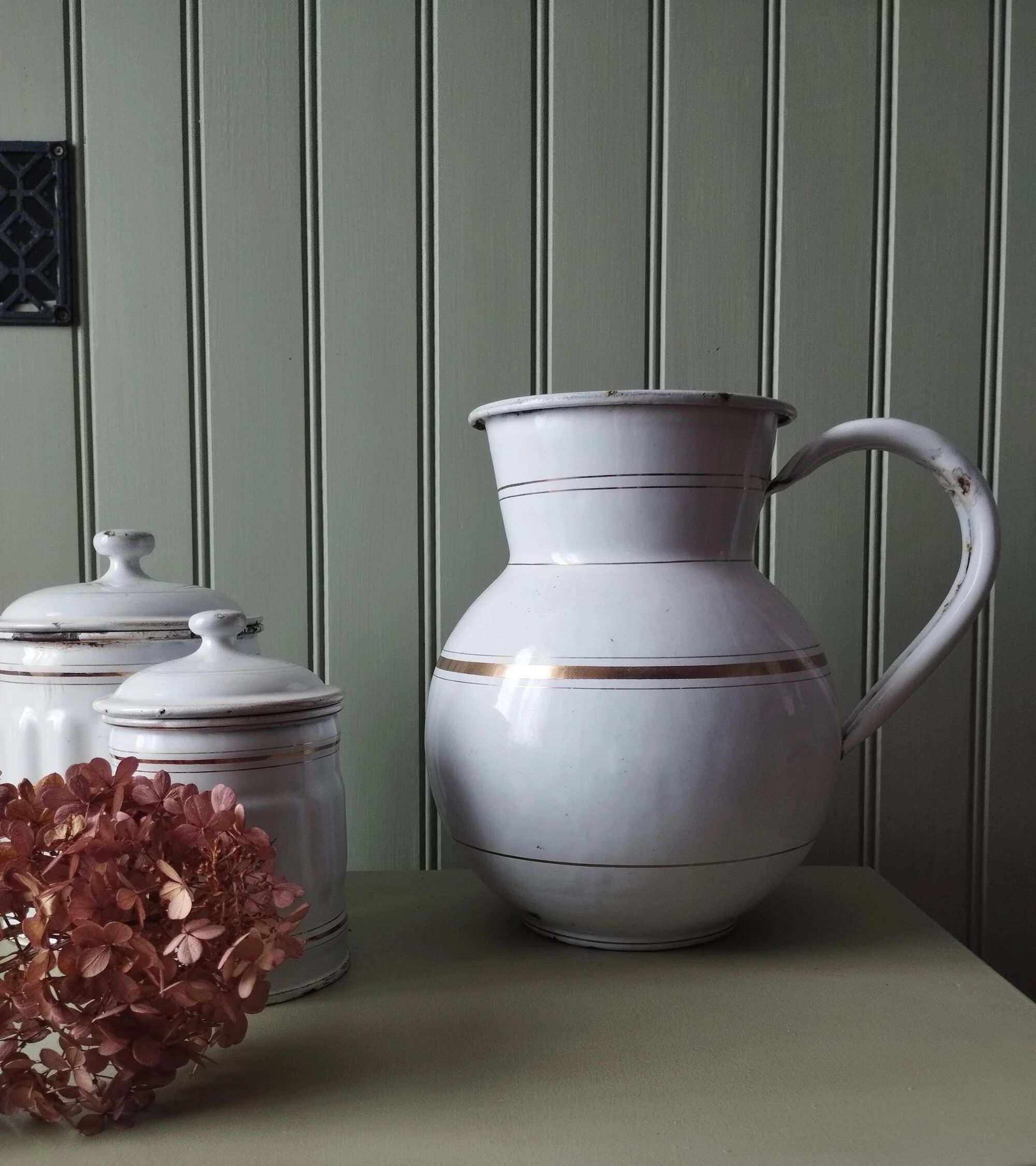 Old enamelled metal jug with gold trim.