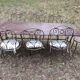 Old wrought iron table and its armchairs and chairs for outdoor use.