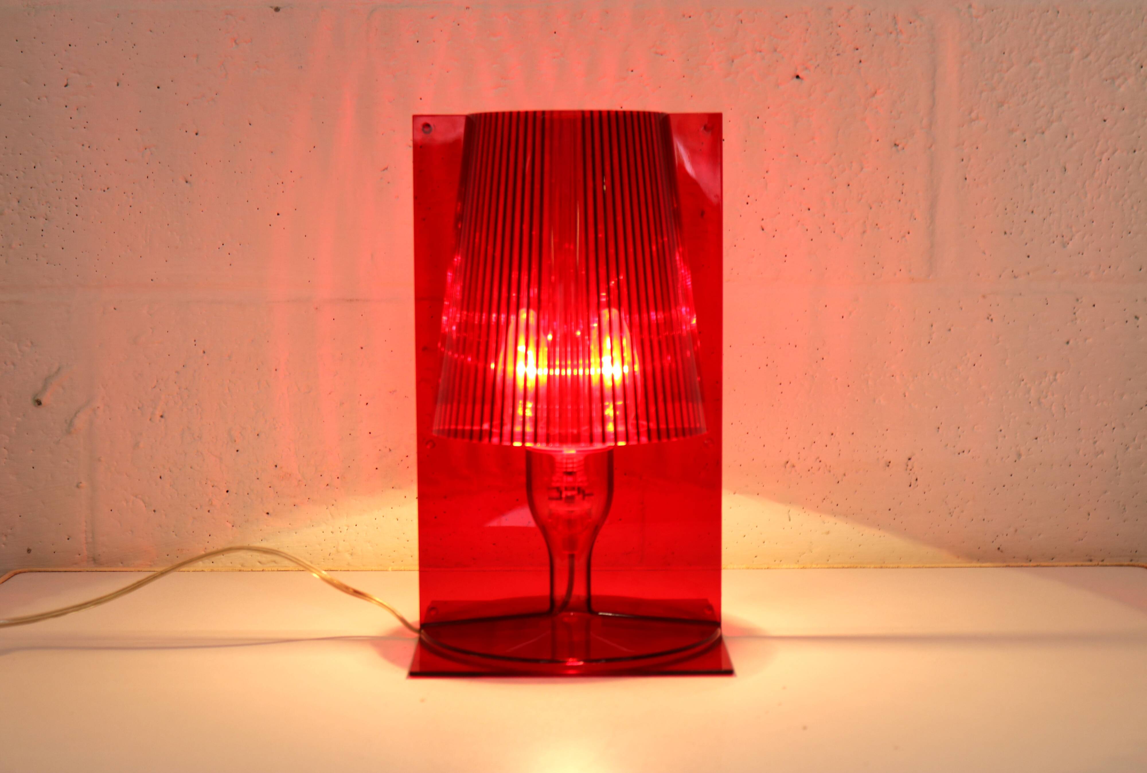 Red plastic Kartell table lamp - model Take - design by Ferruccio Laviani