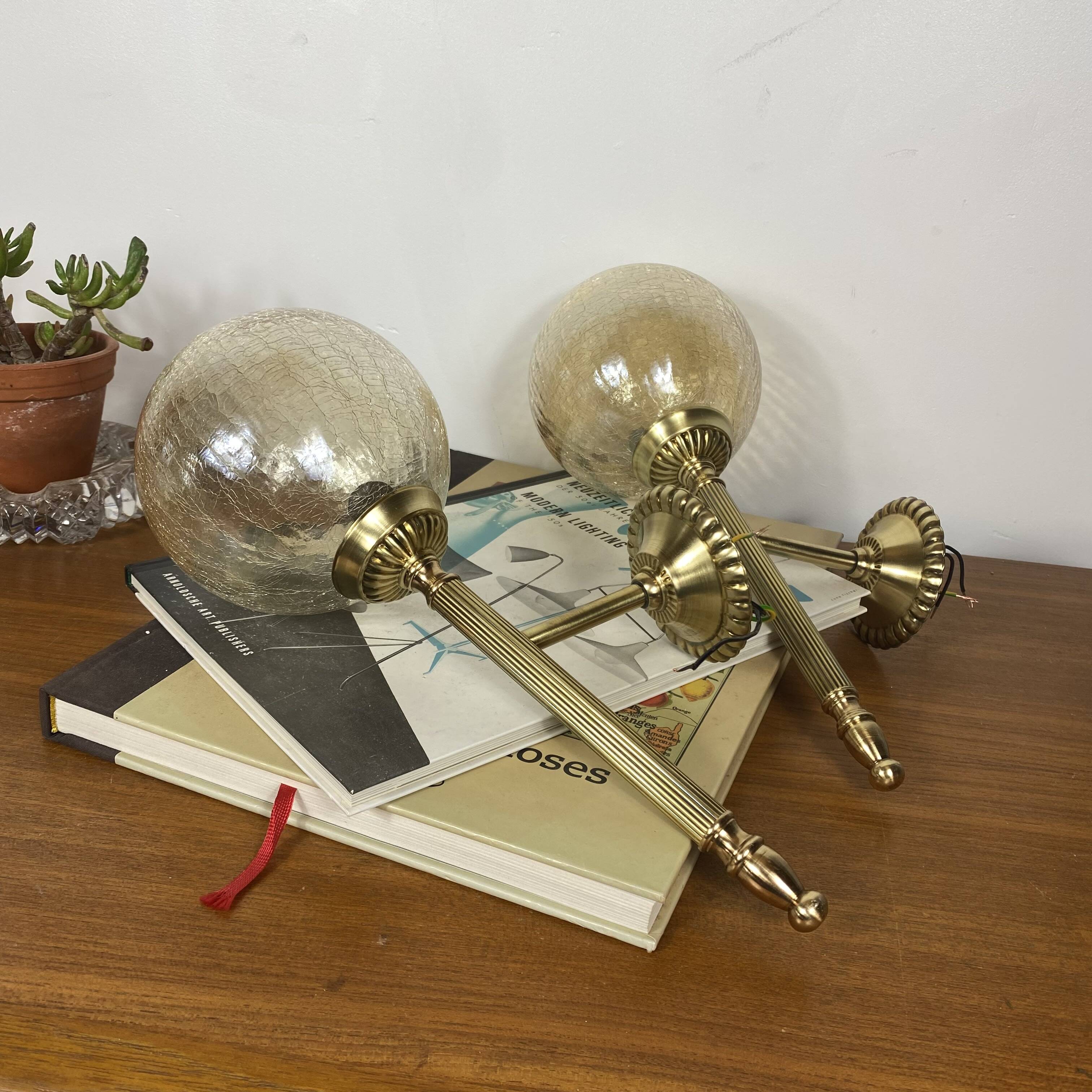 Pair of antique wall sconces torch style brass with glass globes in gold.