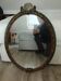 Antique oval mirror in a carved and painted frame with a floral panel.