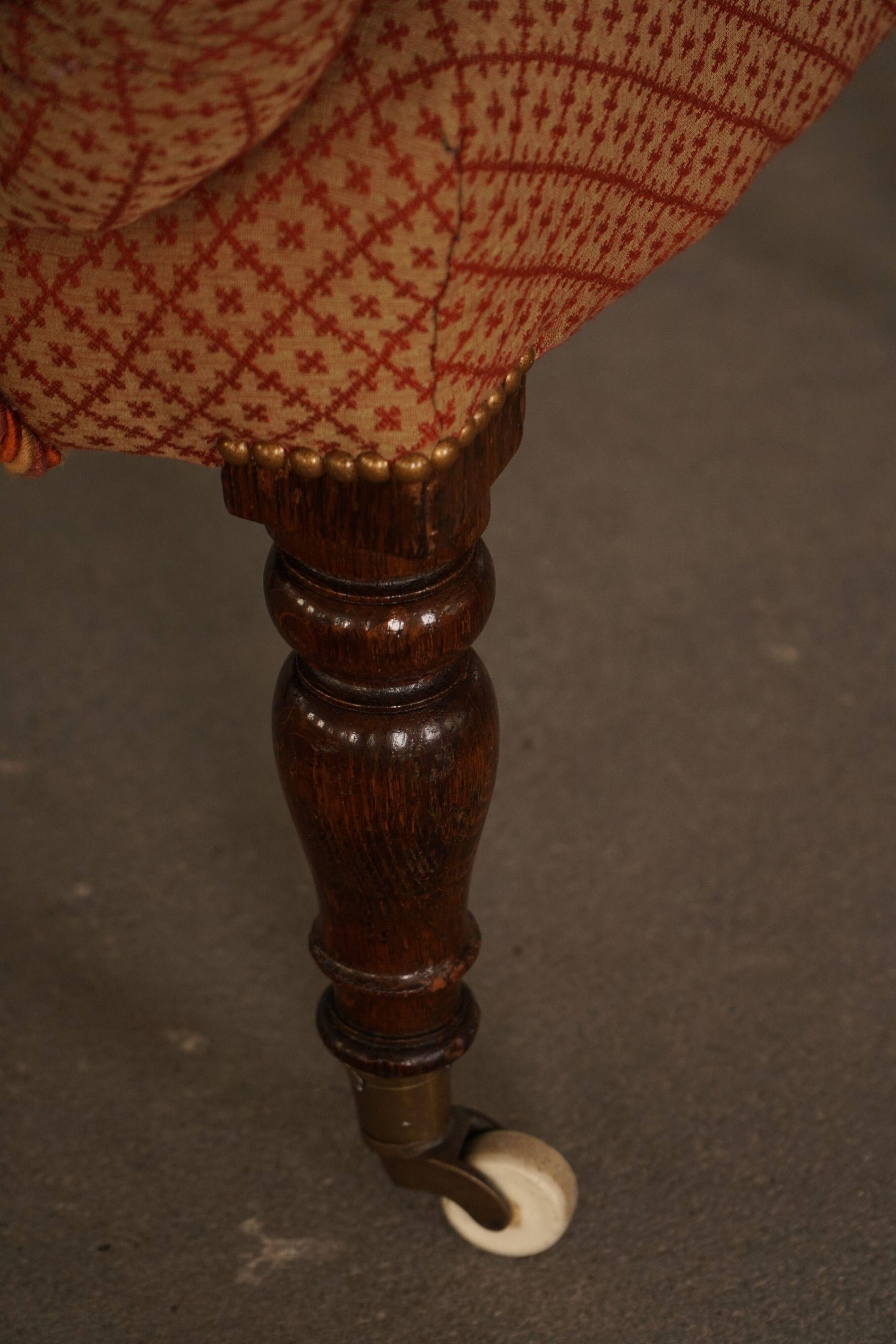 Victorian mahogany armchair, with wheels and coloured fabric, England, early 1900s.