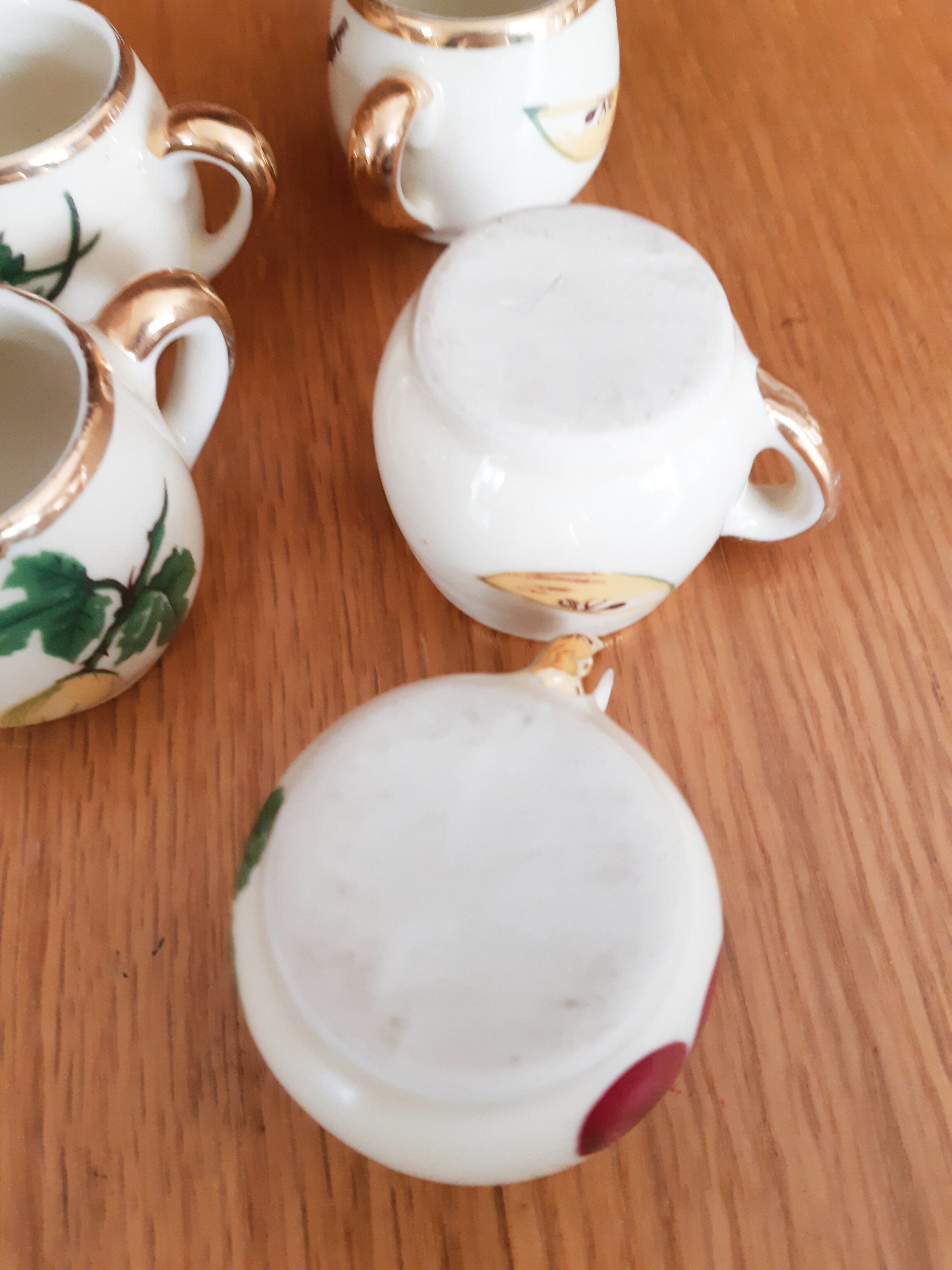 5 antique cups with liquor, porcelain fruits