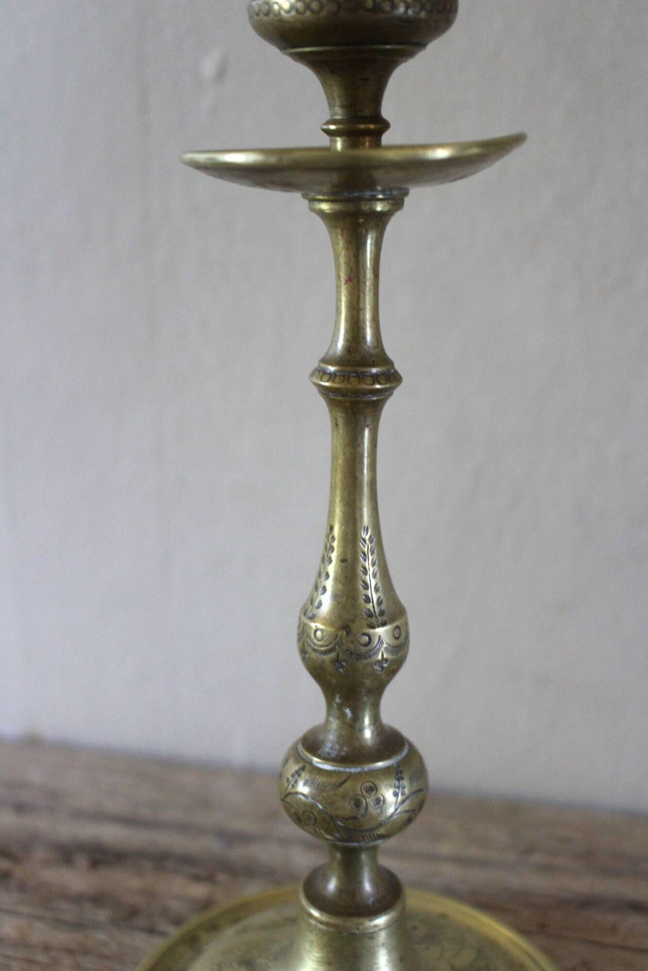 Brass candle holder with flowers and round shape.