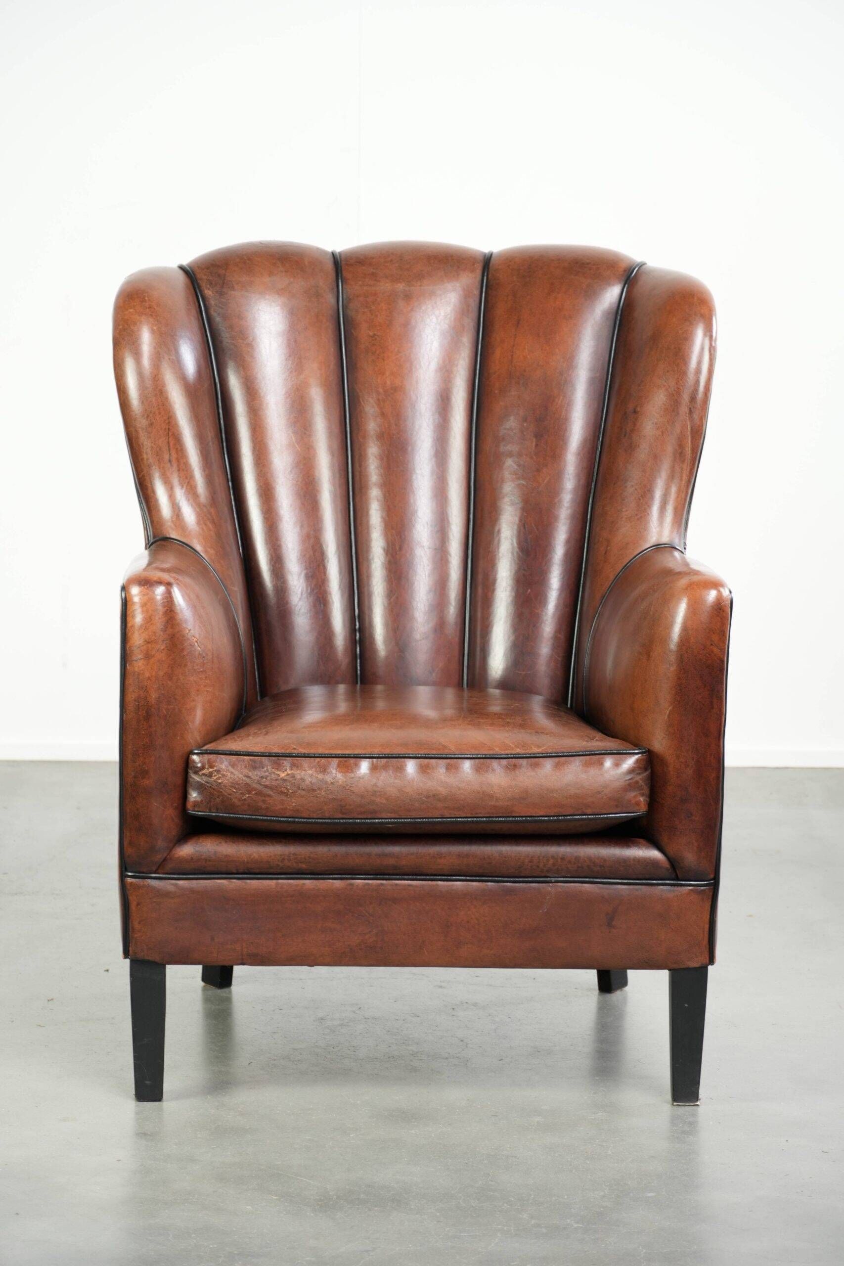 Fauteuil en peau de mouton confortable au design unique, fini avec un passepoil noir.