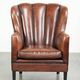Fauteuil en peau de mouton confortable au design unique, fini avec un passepoil noir.