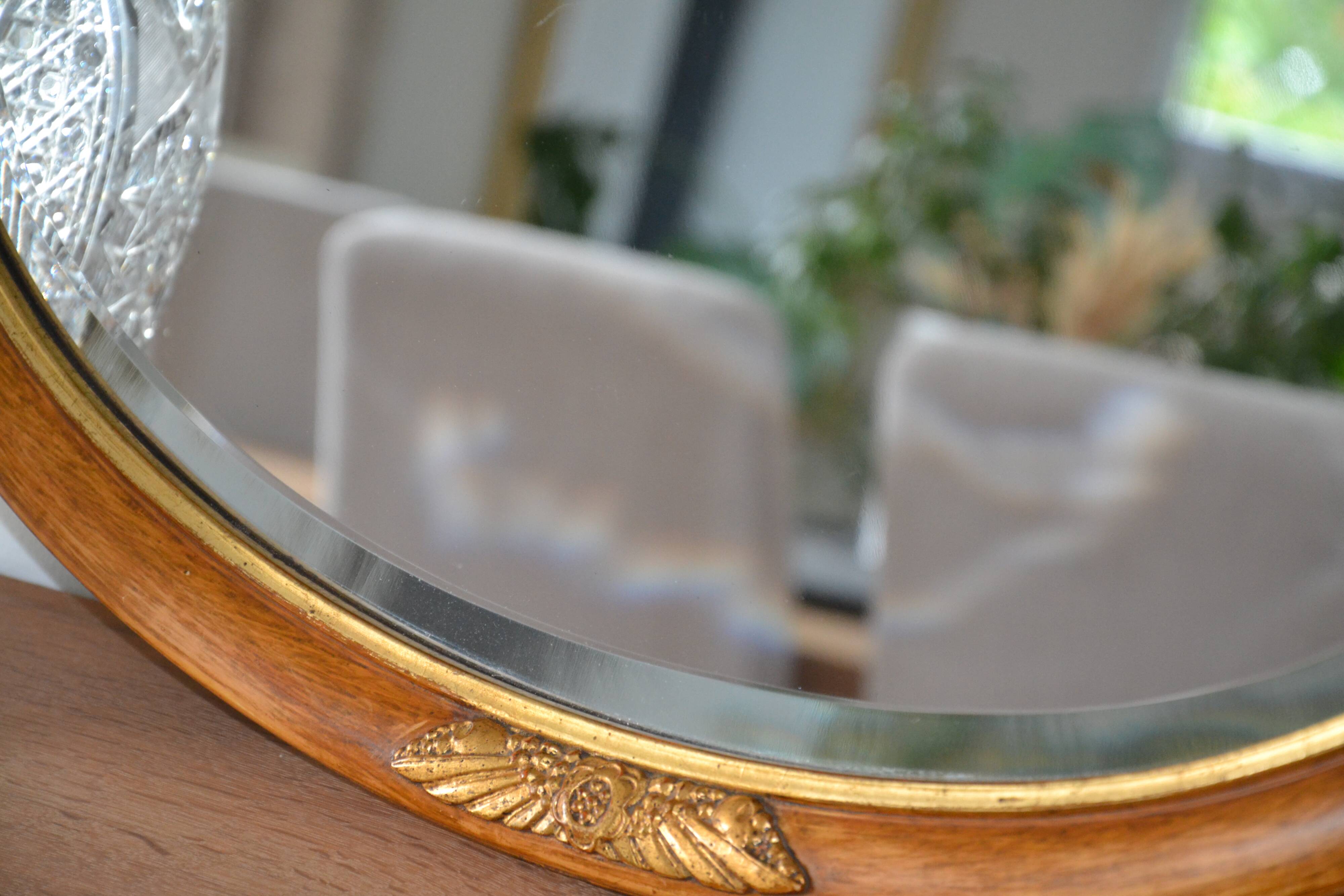 Old oval beveled wooden mirror, partly gilded and carved