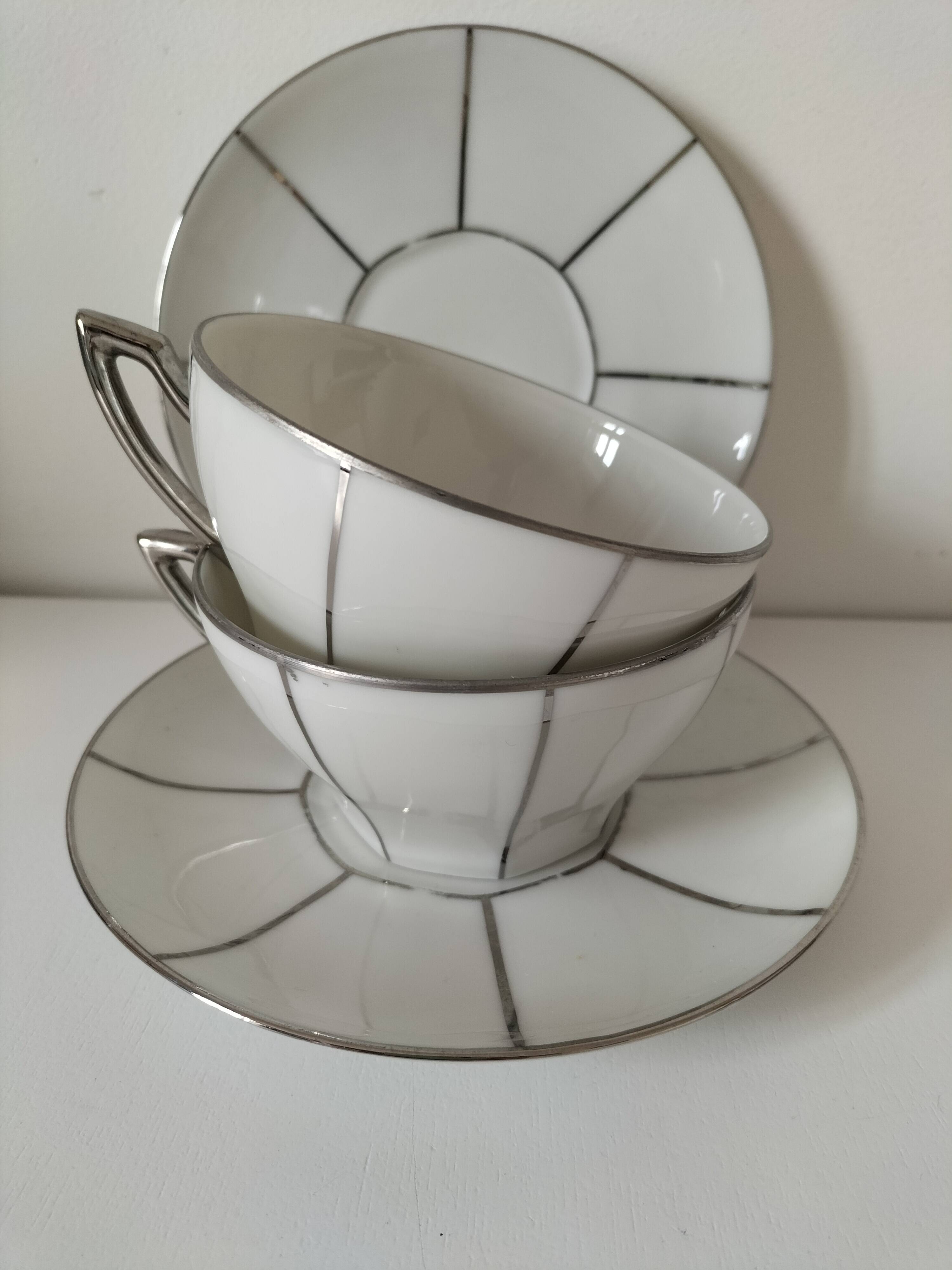 Two Art Deco porcelain cups and saucers with silver trim.
