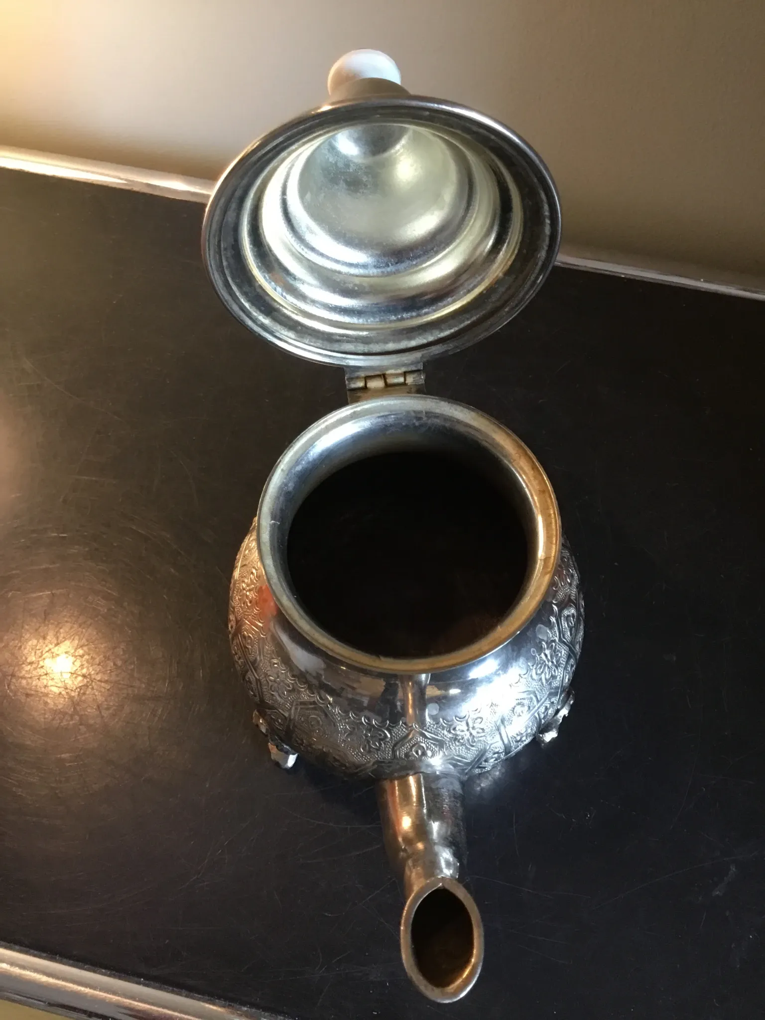 Traditional metal teapot with silver plating, Eastern style, on a stand.