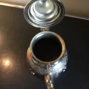 Traditional metal teapot with silver plating, Eastern style, on a stand.
