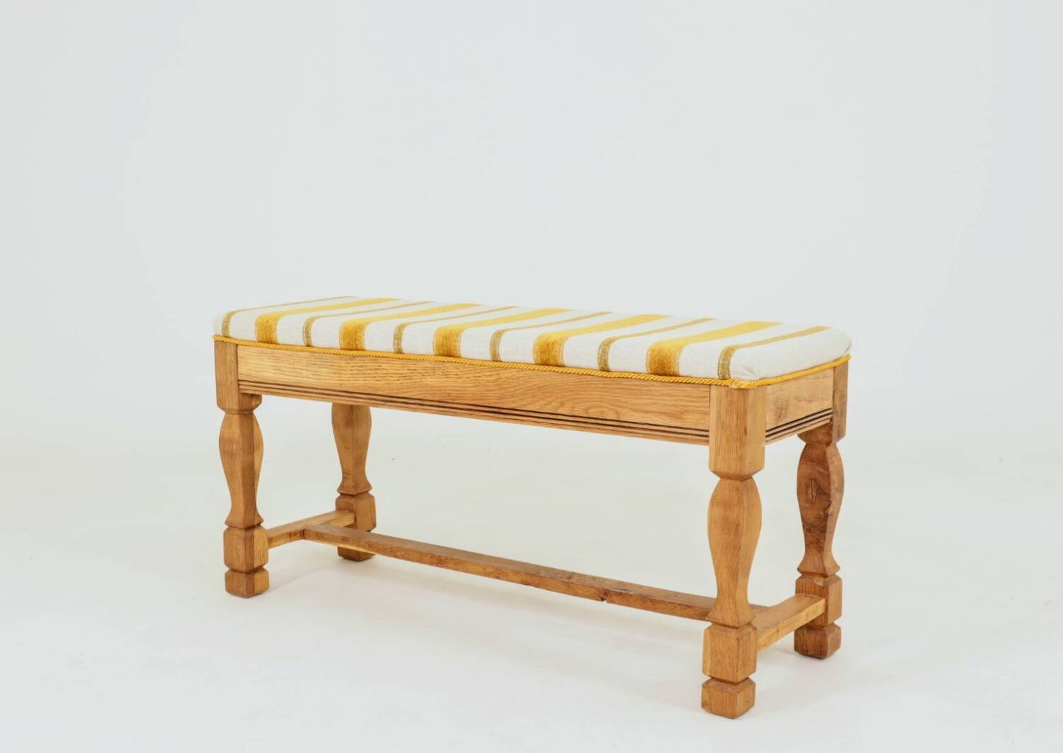 Vintage oak bench with striped linen fabric in a country style.