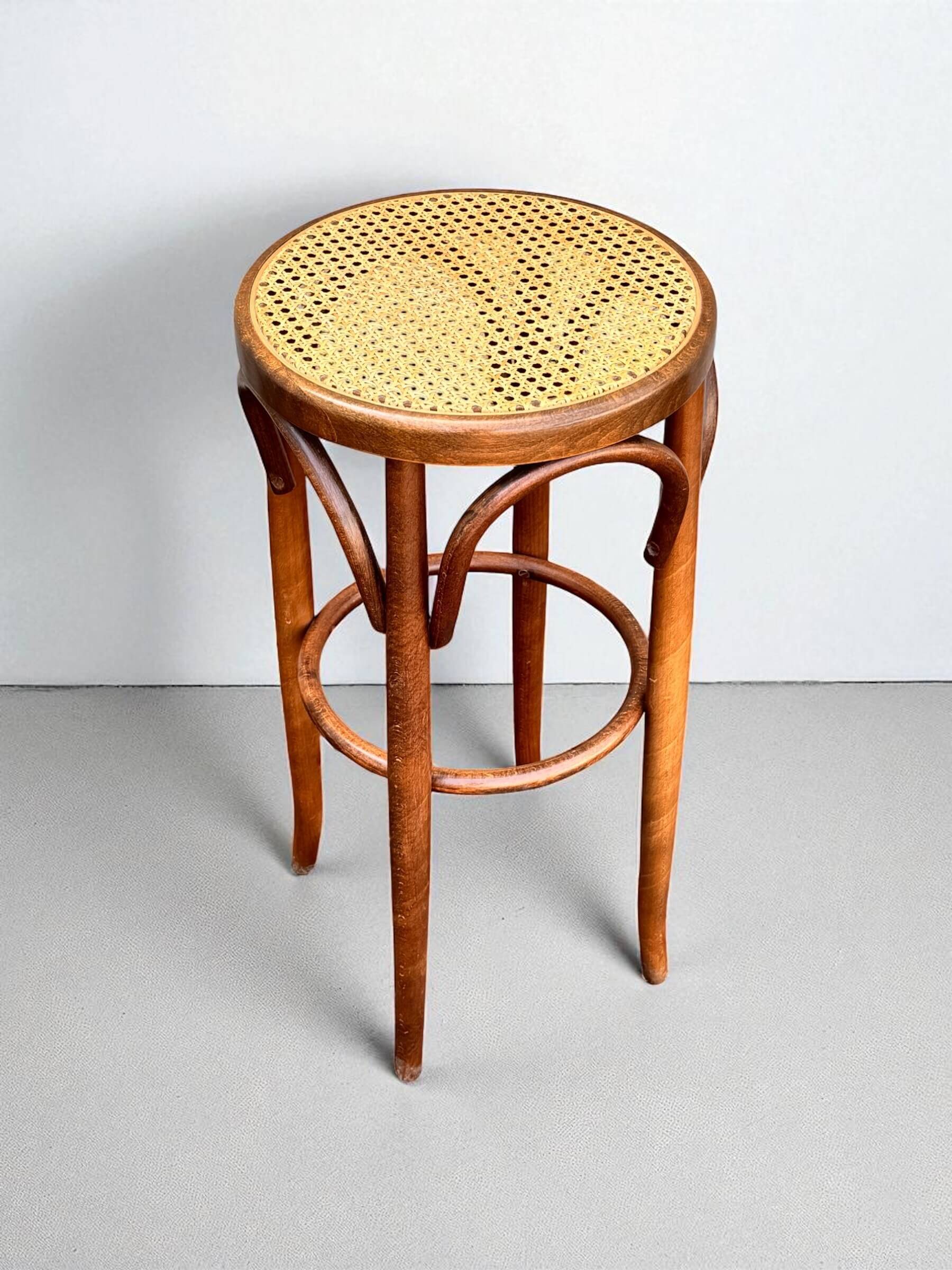 Old high stool in curved wood with caned seat