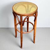 Old high stool in curved wood with caned seat