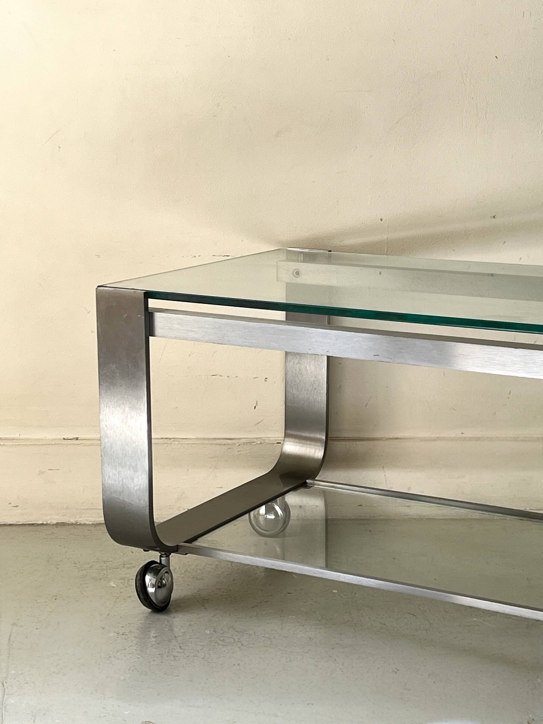 Brushed chrome coffee table with glass, 2 tiers on wheels, 1970s design.