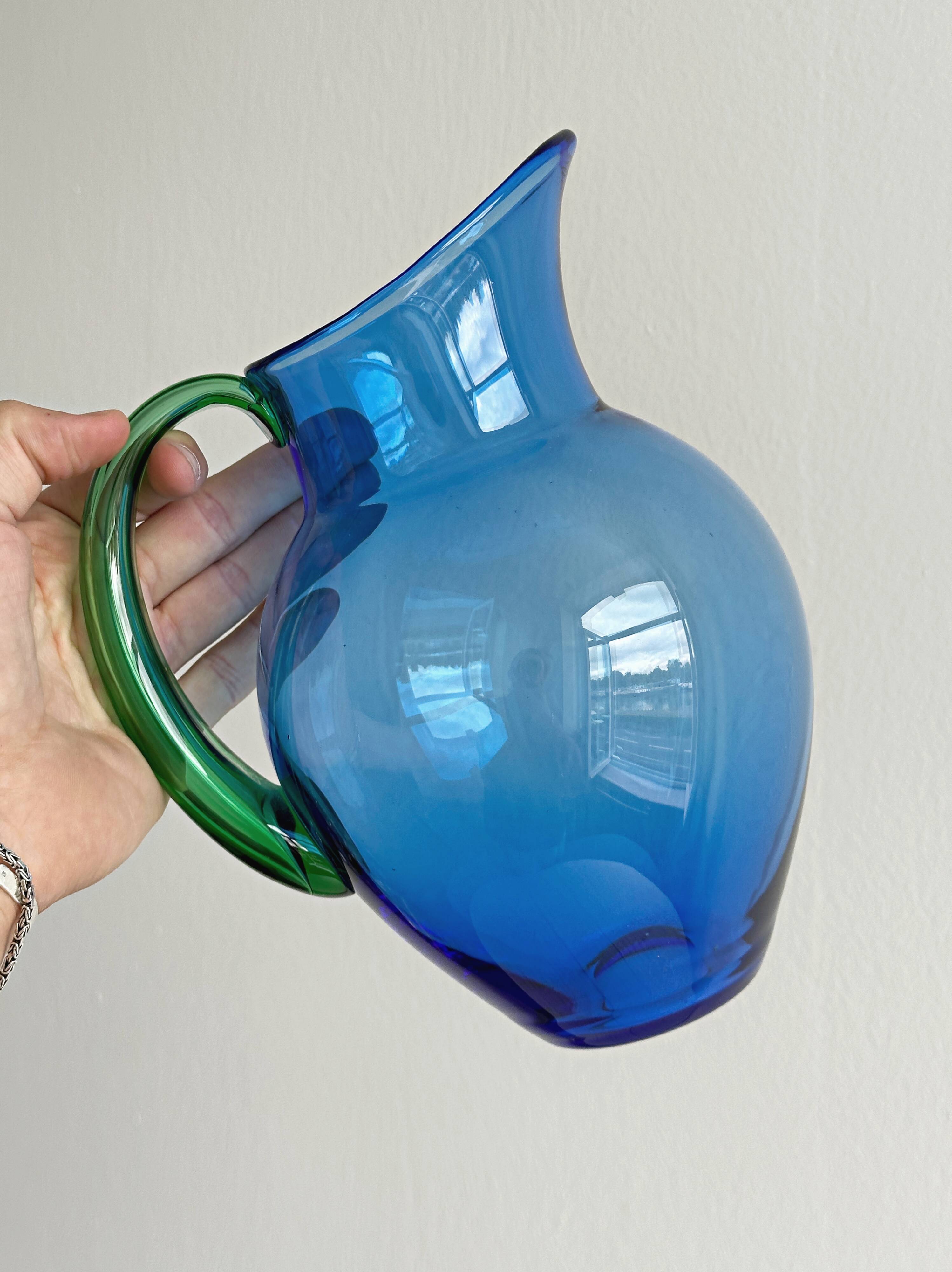 Translucent blue glass jug with a green handle.