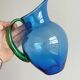 Translucent blue glass jug with a green handle.