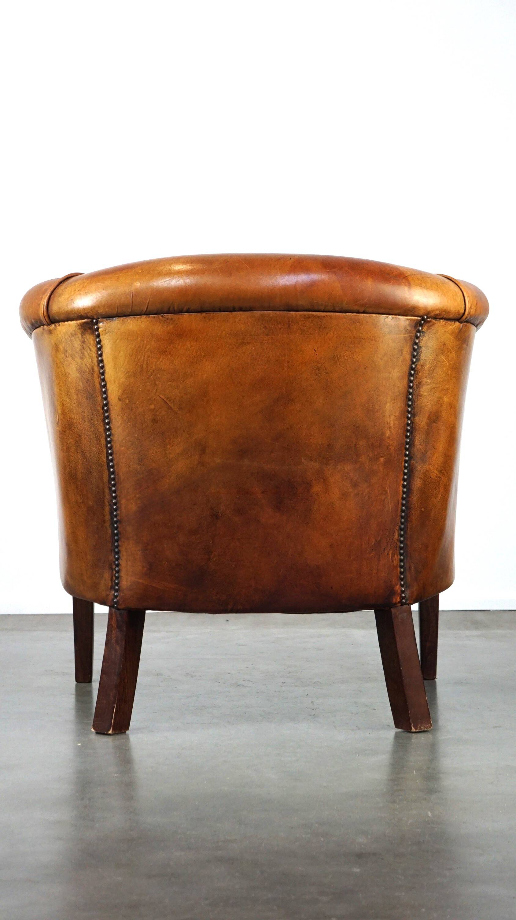 Neat and subtle sheepskin club chair, finished with decorative studs and a fixed seat cushion