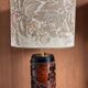 Table lamp with a solid wood printing roll and floral lampshade.