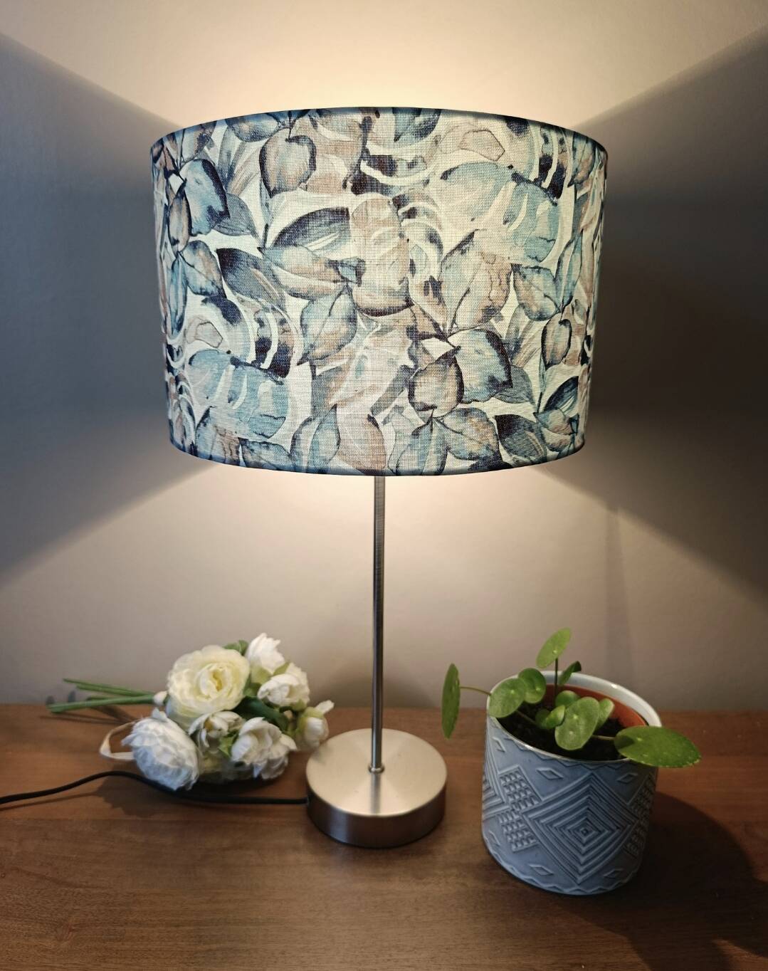 Table lamp with chrome stem, tropical plant shade.