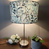 Table lamp with chrome stem, tropical plant shade.