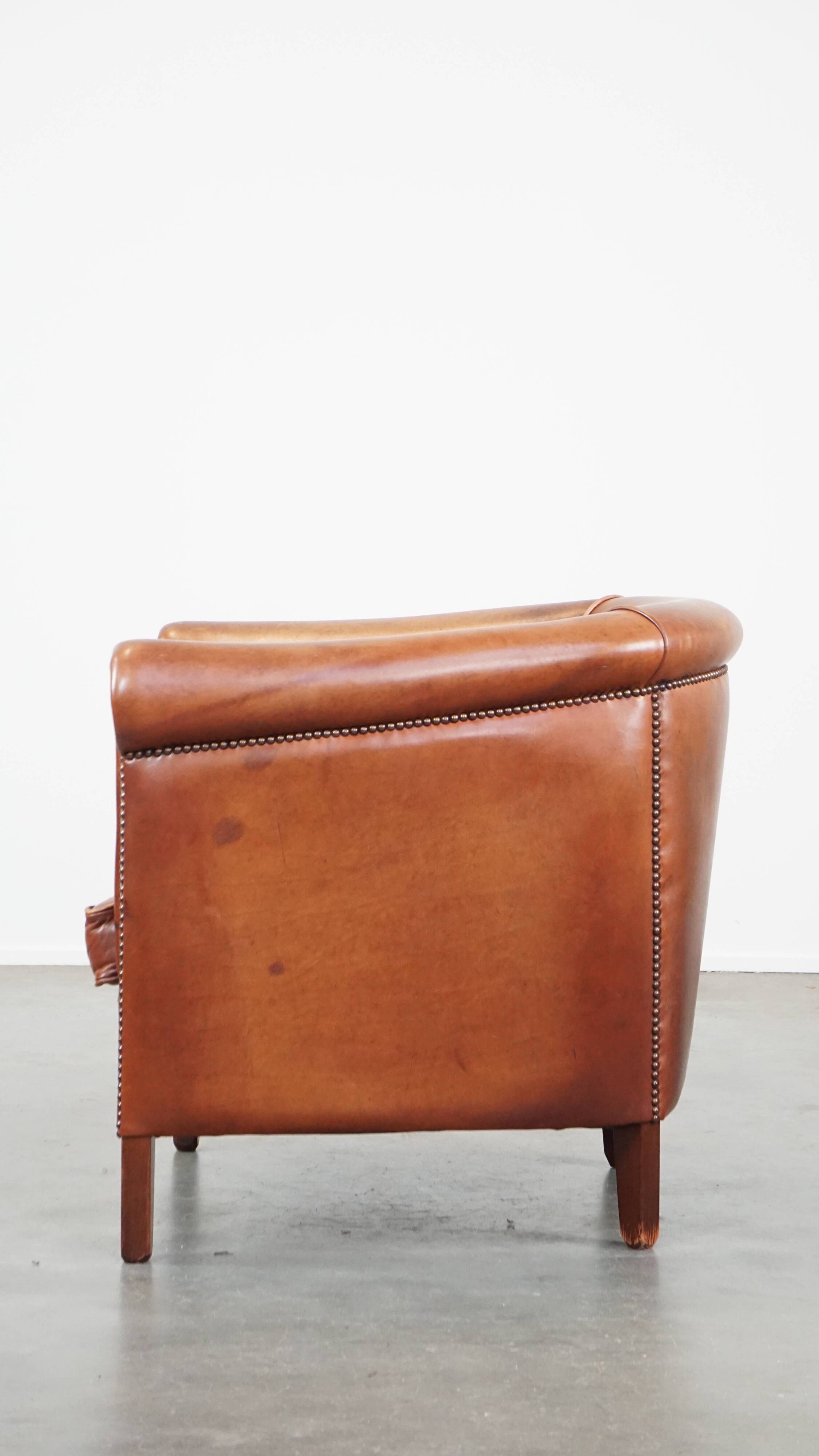 Cognac-colored cow leather club chair finished with decorative nails in English style