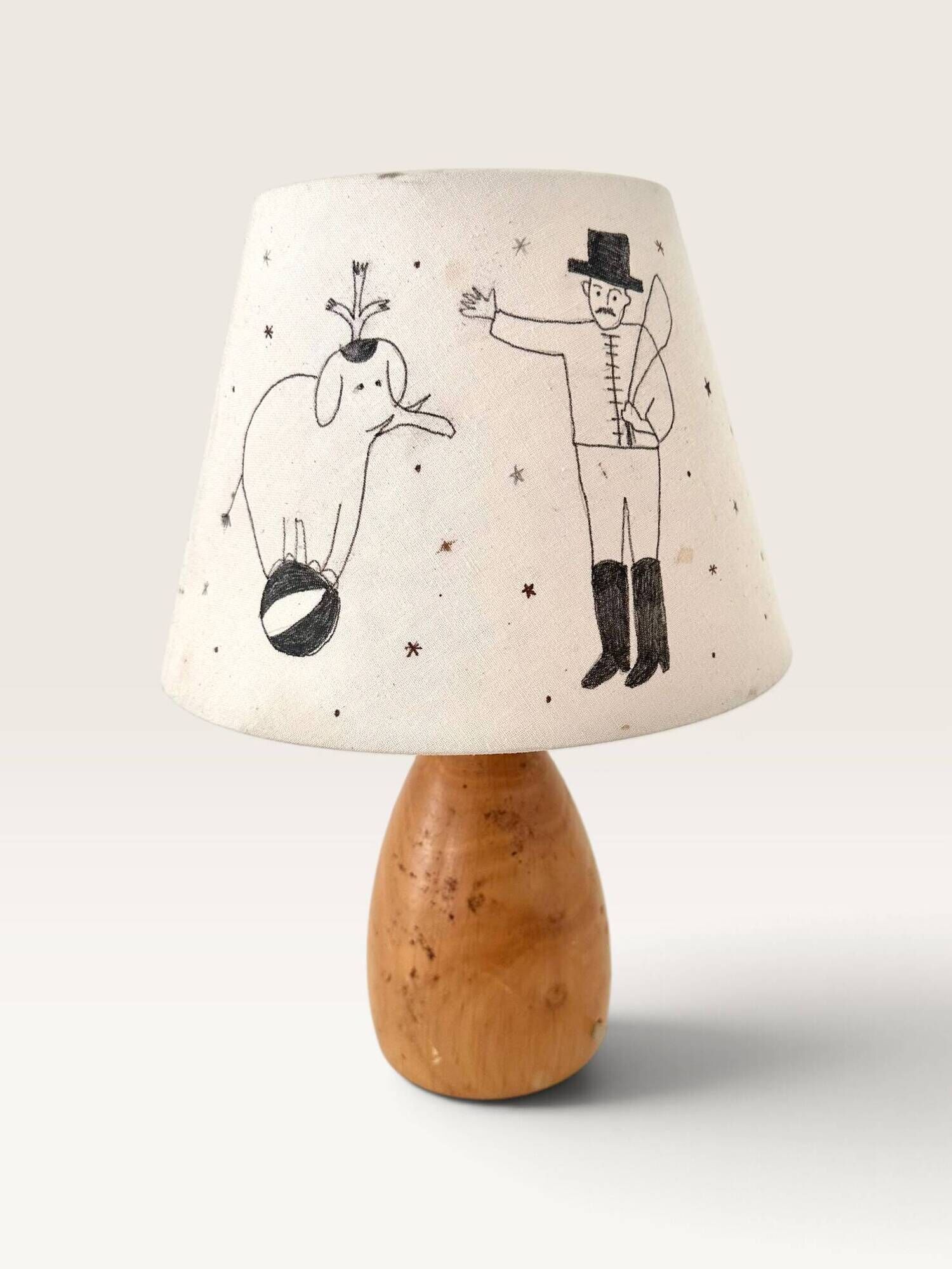 Wood-turned lamp with a hand-drawn lampshade, circus patterns.