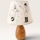 Wood-turned lamp with a hand-drawn lampshade, circus patterns.