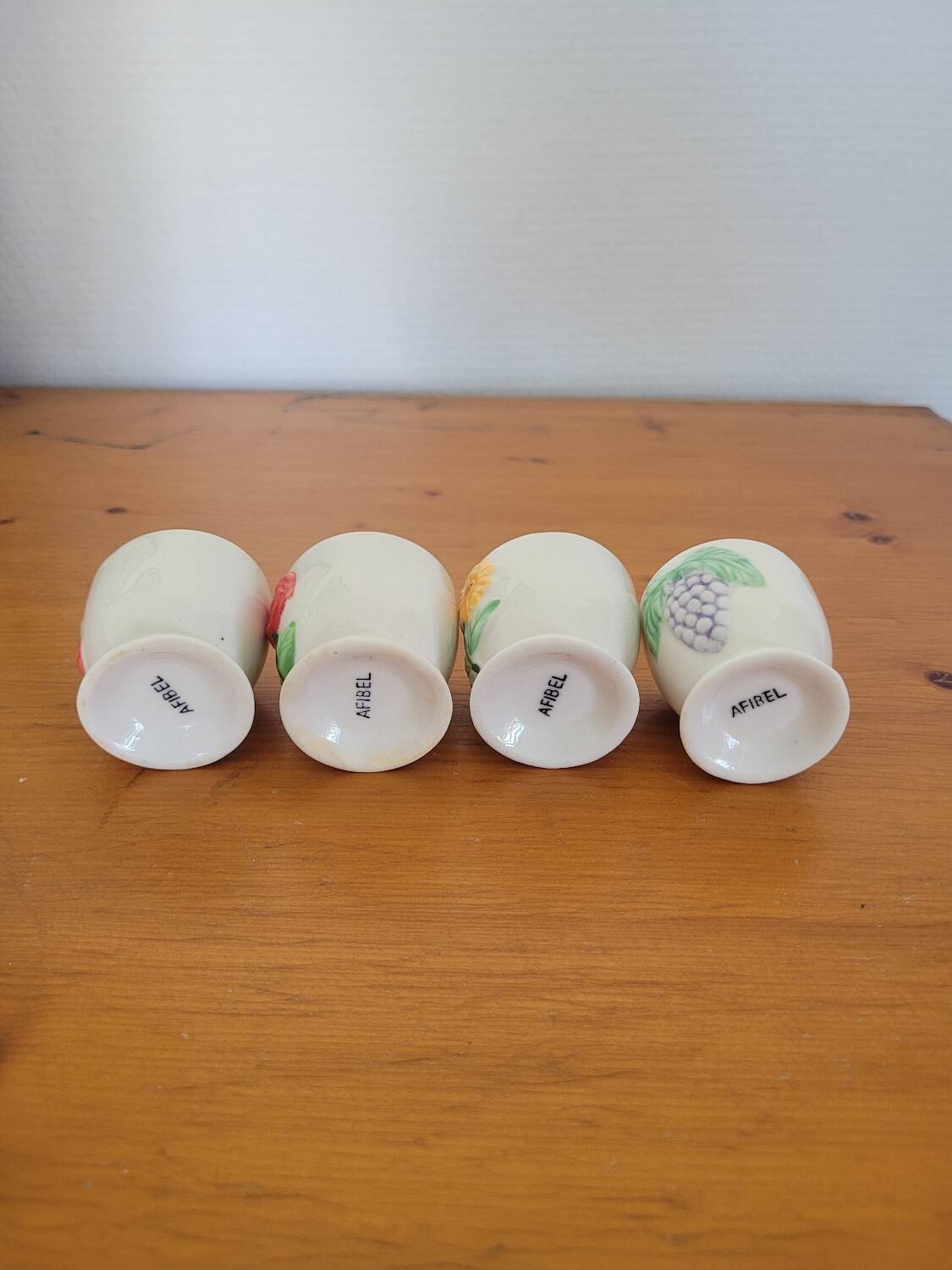 Set of four ceramic egg cups with a floral and fruit pattern.