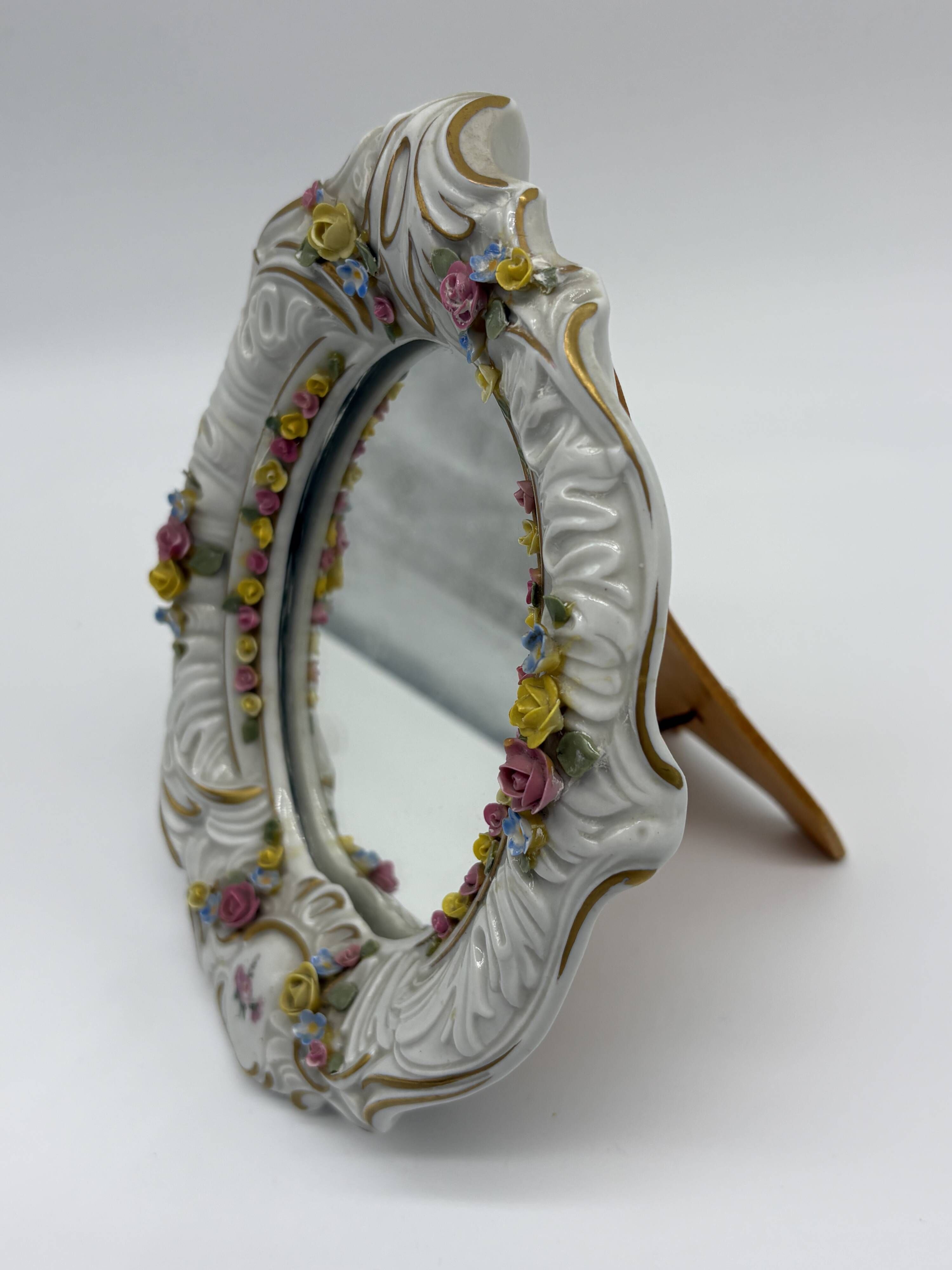Antique porcelain mirror from Dresden with relief flowers and rococo decoration.
