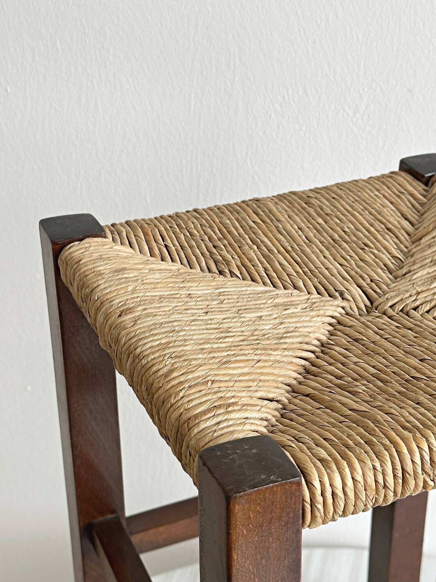 Vintage stool in dark wood with a woven straw seat.