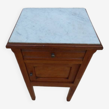 Antique bedside table with its marble top and white earthenware interior