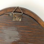 Antique wall mirror in carved wood with a wavy shape and a golden trim.