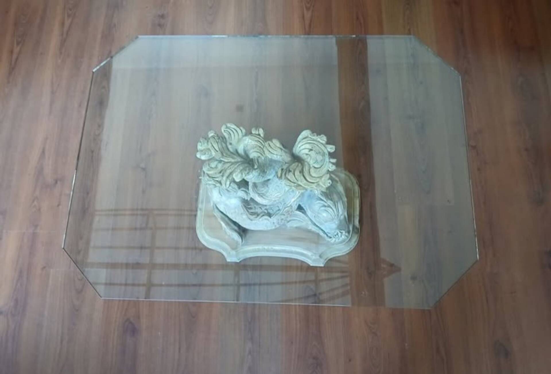 Glass table with carved wooden legs featuring intertwined fish.