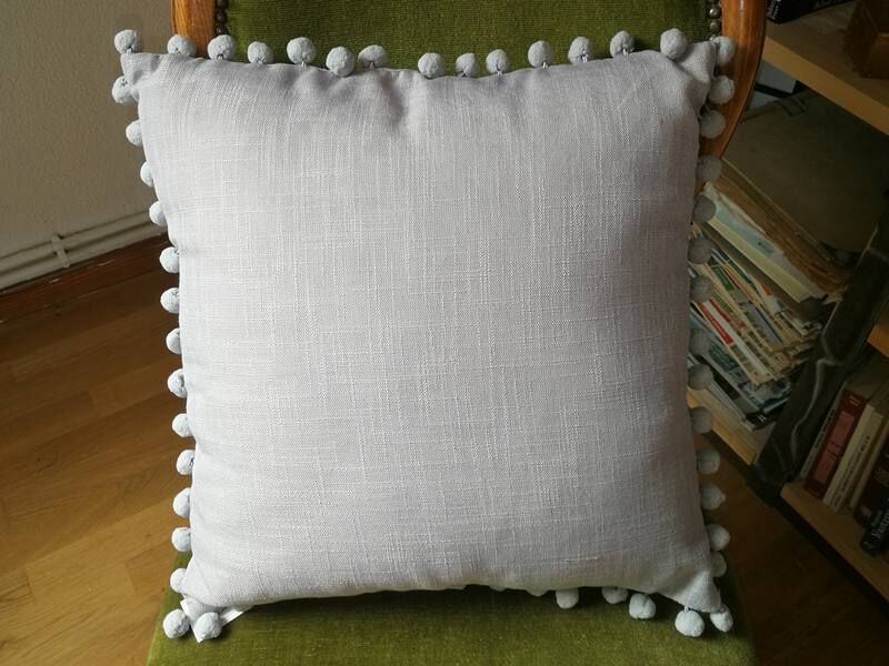 Gray cushion with pompoms