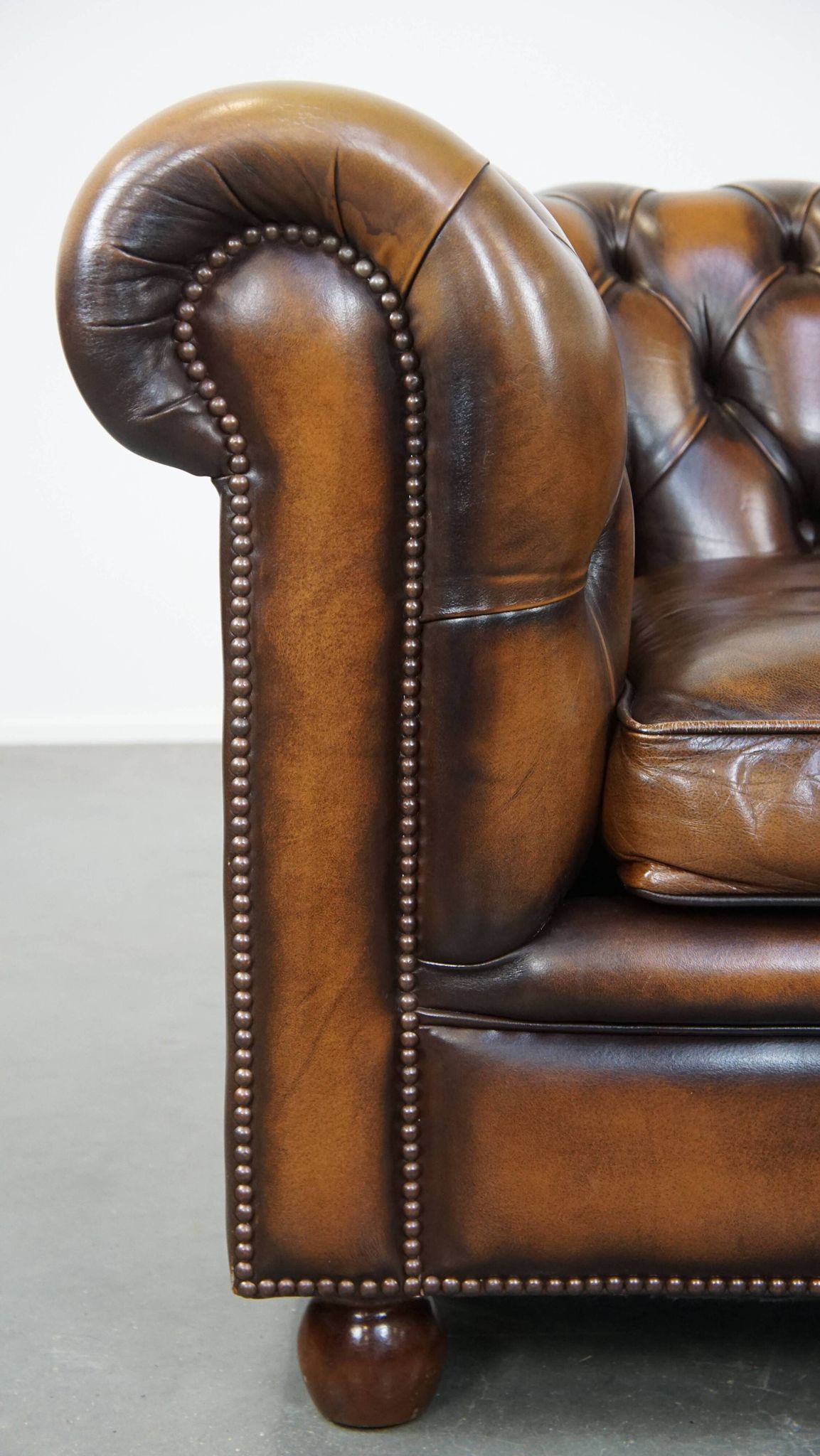 A well-maintained cowhide leather English Chesterfield armchair
